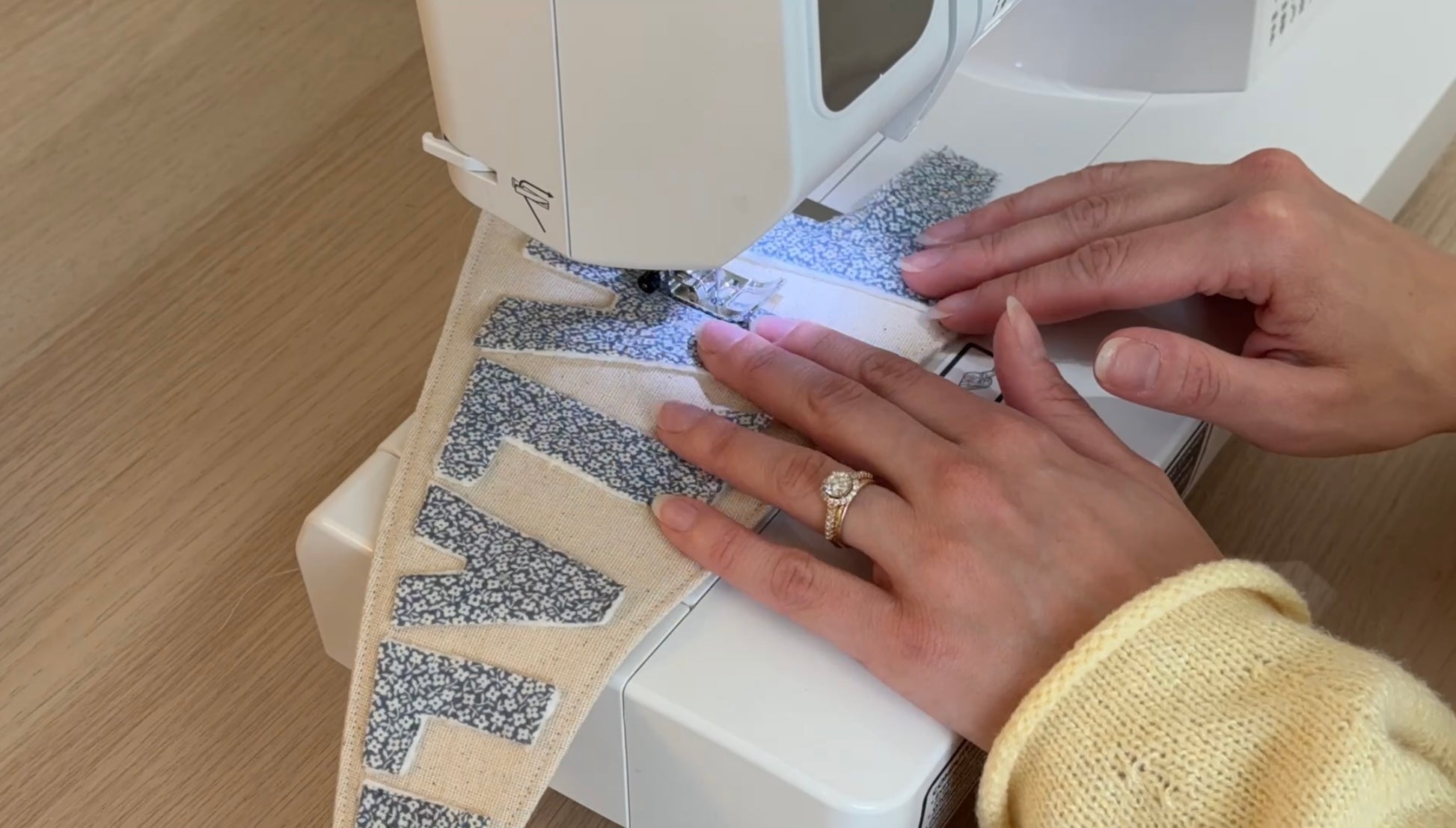 Person using a sewing machine to sew fabric letters on to a pennant flag.